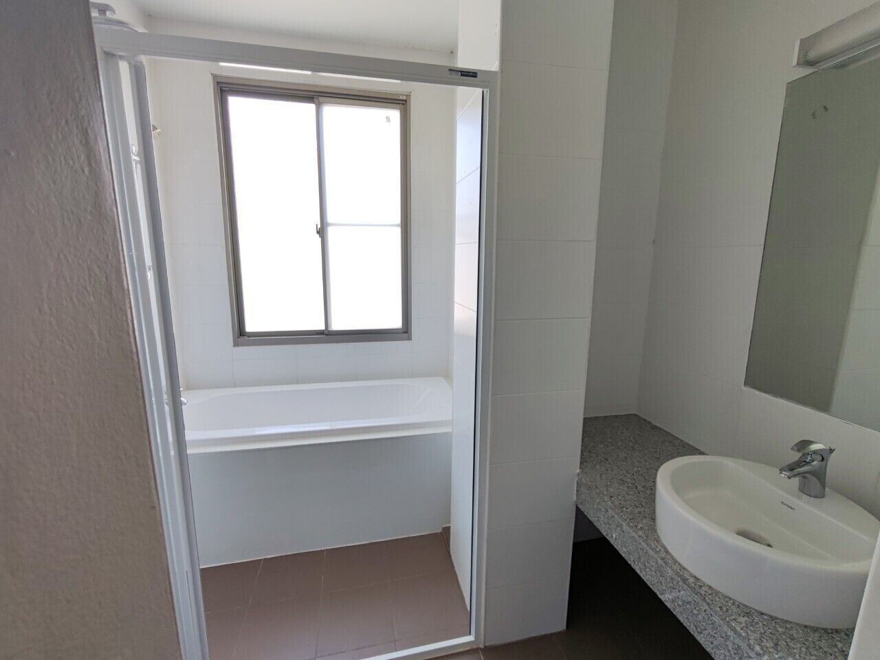 Un baño con ventana, lavabo y espejo.