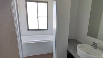 Un baño con ventana, lavabo y espejo.