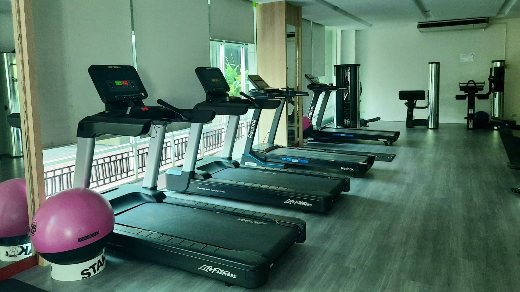 A row of treadmills in a gym with a view of the outside.