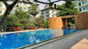 Ein Pool mit Holzsteg, Liegestühlen und einer Palme.