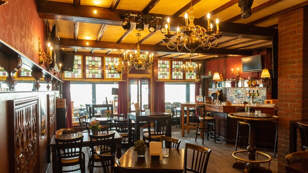 A restaurant interior with multiple dining tables and chairs, chandeliers, and a bar area. - Hotel en Grand Café de Pauw (Roermond)