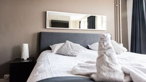 A hotel room with a neatly made bed, a bedside table with a lamp, and a large mirror on the wall. - Hotel en Grand Café de Pauw (Roermond)
