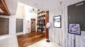 Eine Hotelhalle mit Holzboden, einer Rezeption, einem Bücherregal und einem an der Wand montierten Fernseher.