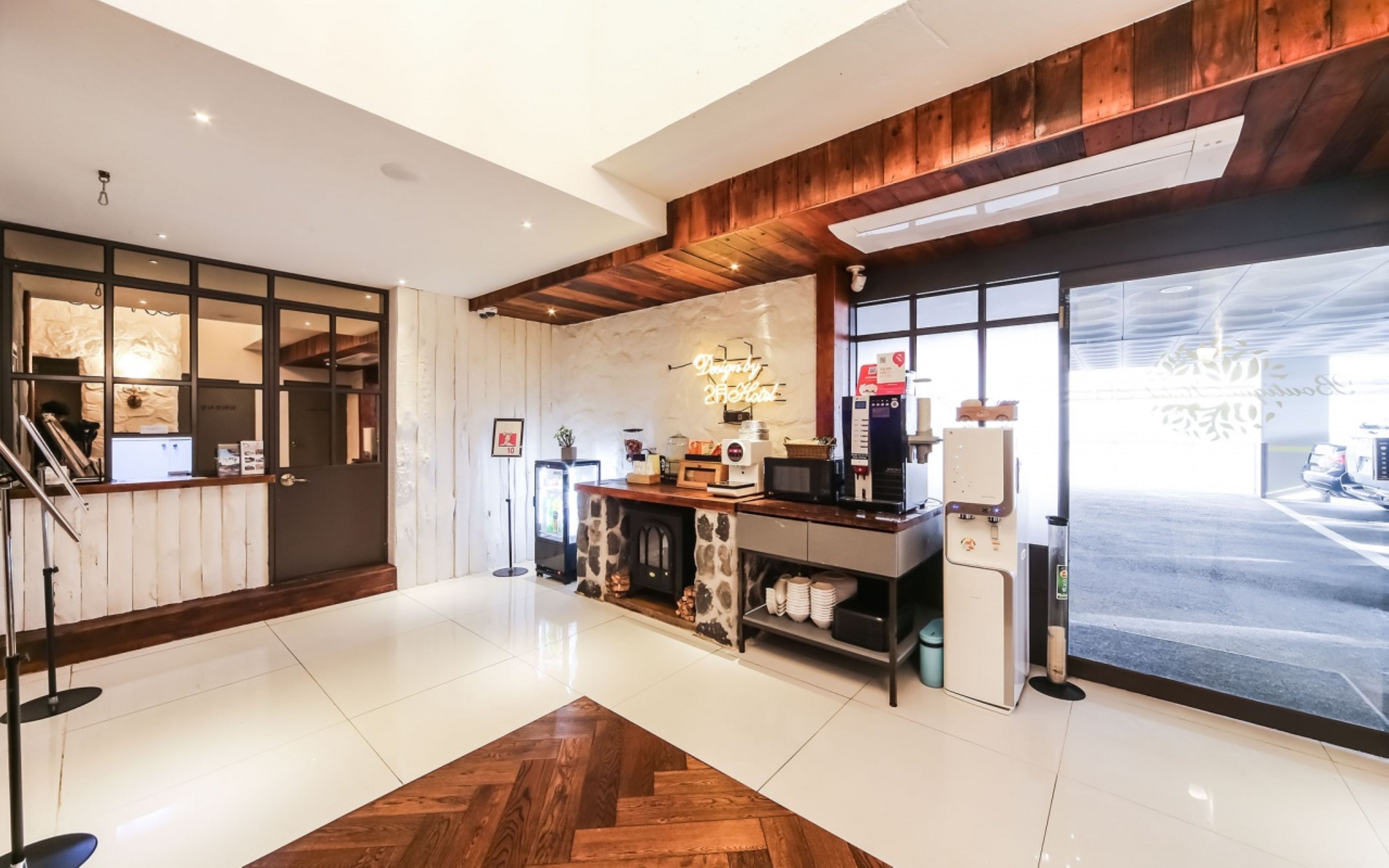 Un interior moderno con techo de madera, una recepción, una máquina de café y un ventanal grande.