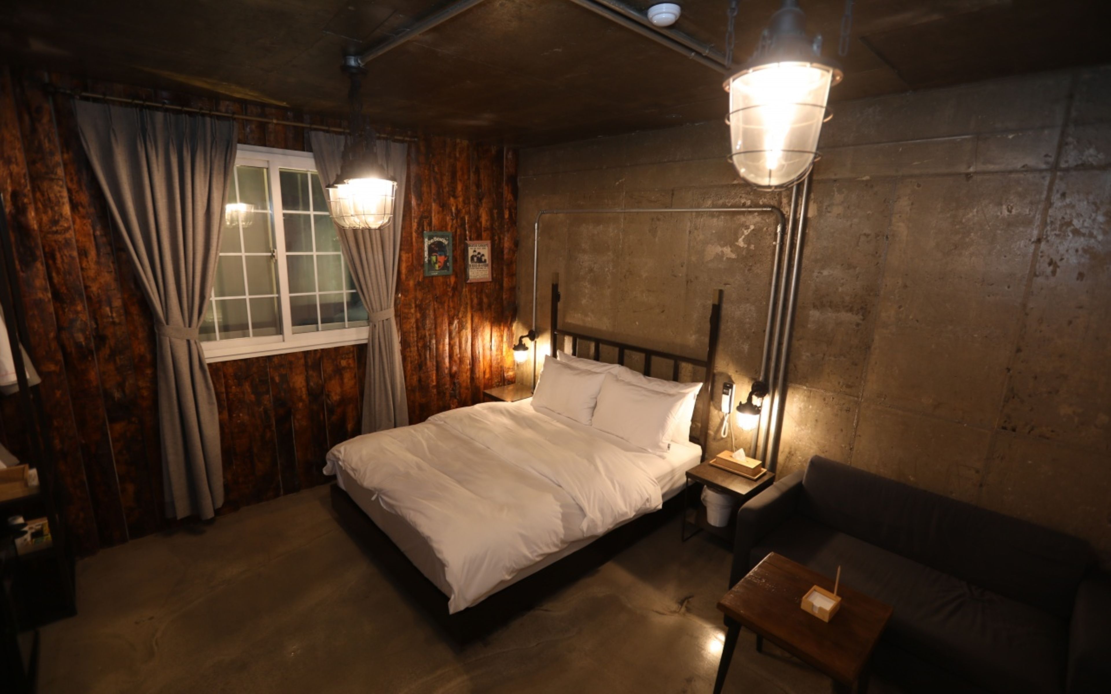 Een kamer met een bed, een nachtkastje, een tafel en een bank.