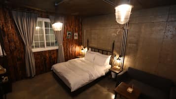 Een kamer met een bed, een nachtkastje, een tafel en een bank.