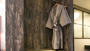 A wooden wall with a robe hanging on a rack, a shelf with toiletries, and a small refrigerator. - February Hotel Songdo Amnam (Busan)