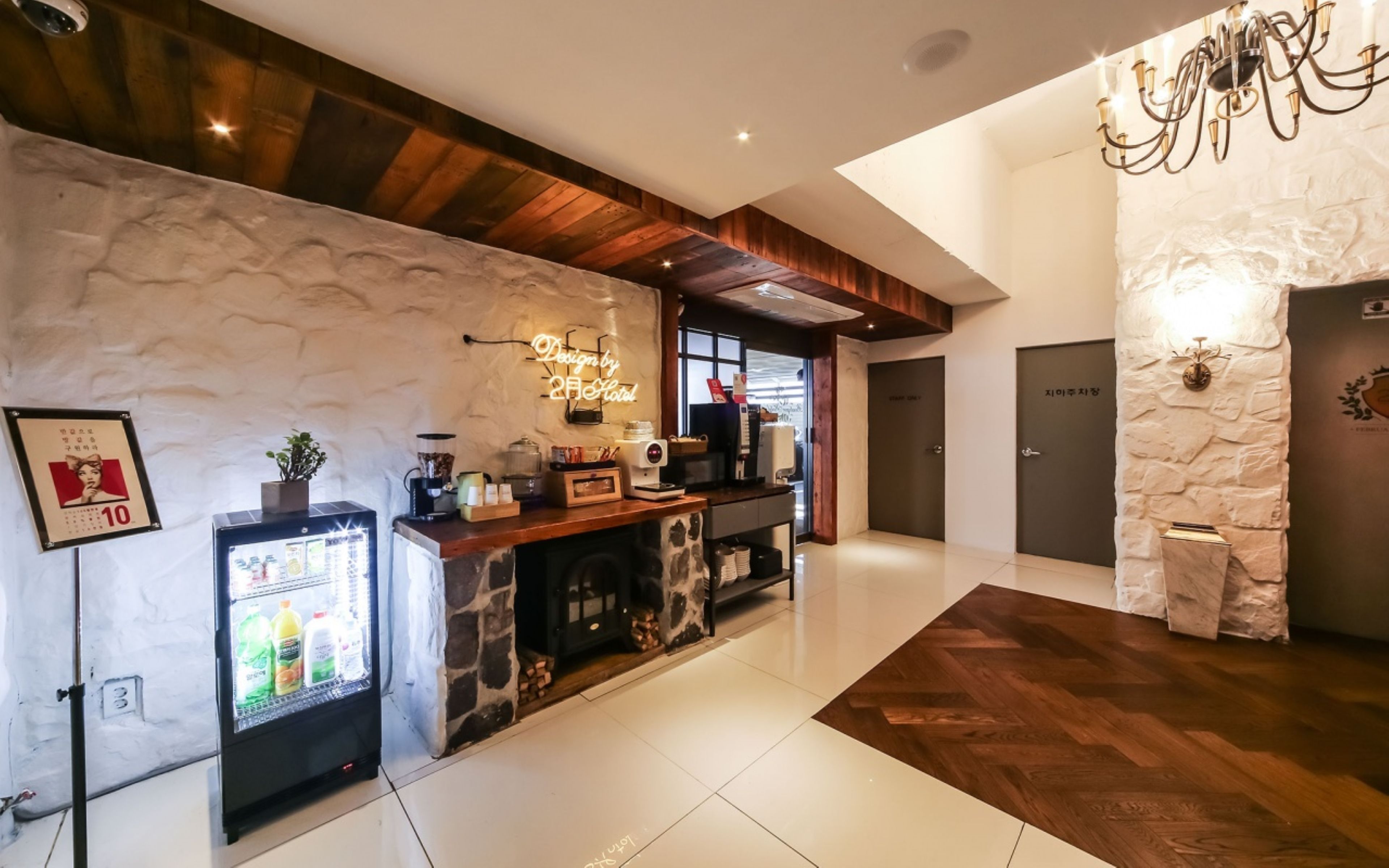 Un hall d’hôtel comprenant un comptoir d’accueil, un réfrigérateur, une machine à café et un mur en pierre.