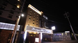 A hotel entrance with illuminated signage, a brick facade, and a parking area. - February Hotel - Busan Songdo (Busan)