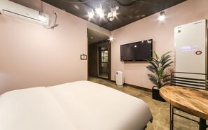 A hotel room with a bed, a flat-screen TV mounted on the wall, a small potted plant, and a wall-mounted air conditioner. - February Hotel - Busan Songdo (Busan)