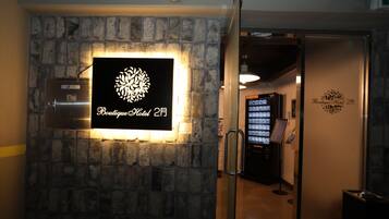 Señal en la pared para el Boutique Hotel 2F con un emblema decorativo, una máquina expendedora y una entrada por puerta de vidrio.