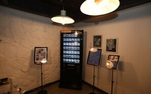 A room with a vending machine, framed pictures on the wall, and a textured wall. - February Hotel - Busan Songdo (Busan)