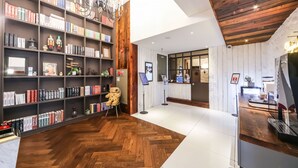 A modern library with bookshelves, a wooden floor, and a reception desk. - February Hotel - Busan Songdo (Busan)