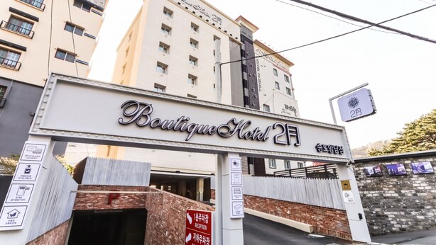 A hotel entrance with a sign reading 'Boutique Hotel 2F' and a reception sign pointing to the right. - February Hotel - Busan Songdo (Busan)