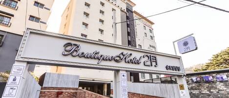 A hotel entrance with a sign reading 'Boutique Hotel 2F' and a reception sign pointing to the right.