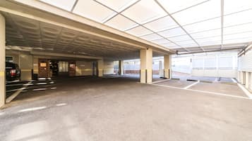 A covered parking area with concrete flooring and a flat ceiling.