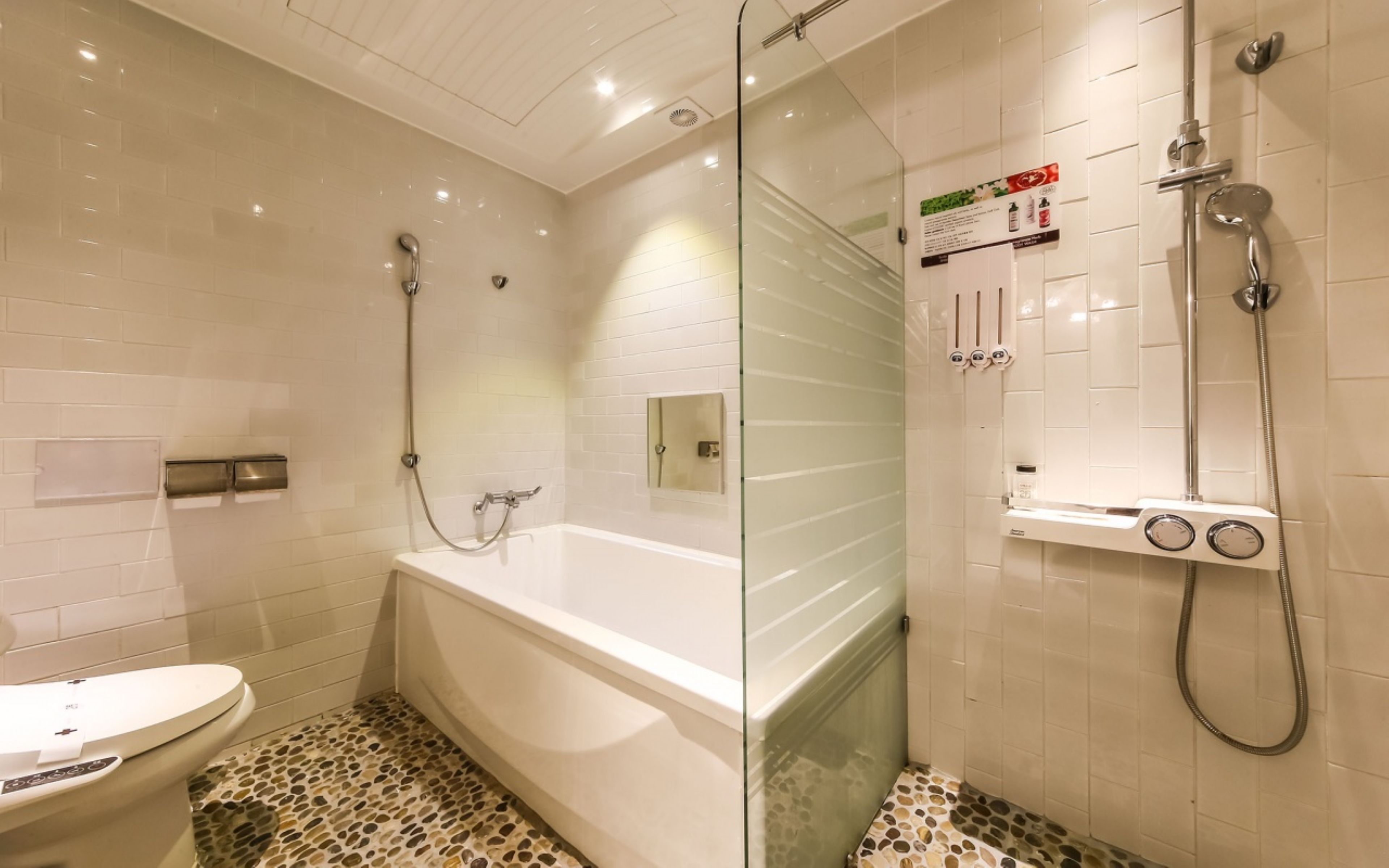 A modern bathroom with a bathtub, a glass-enclosed shower area, and a toilet.