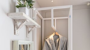 A bathroom with a wooden vanity, a robe hanging on a rack, a mirror, and a shelf with toiletries. - February Hotel Songdo Amnam (Busan)