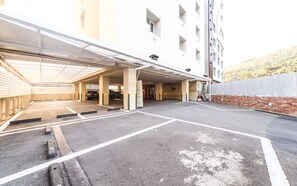 A parking garage with multiple levels, a covered entrance, and a brick wall on one side. - February Hotel - Busan Songdo (Busan)
