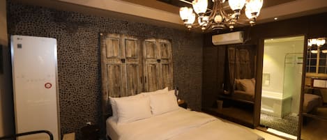 A bedroom with a bed, a wardrobe, a mirror, and a chandelier.