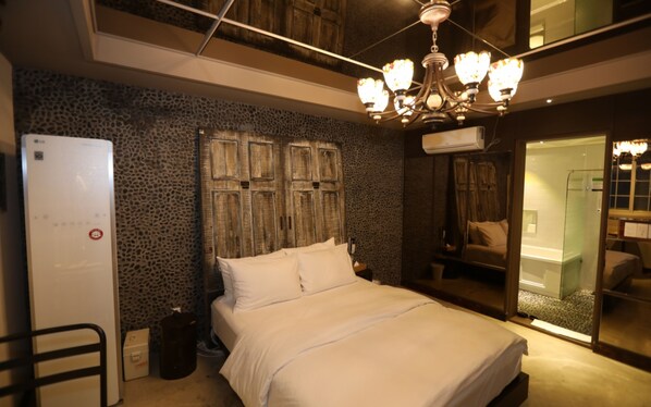 Une chambre à coucher avec un lit, une armoire, un miroir et un lustre.