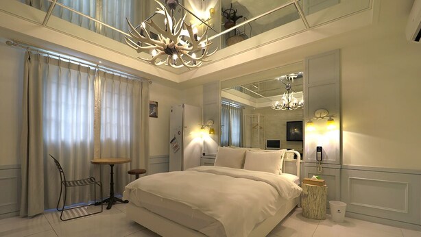 A modern hotel room with a large bed, a small table, a chair, a mirror, and a chandelier. - February Hotel Songdo Amnam (Busan)