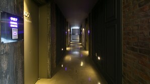 A hotel corridor with a sign for room 907, a reception area, and a brick wall on the right. - February Hotel Songdo Amnam (Busan)