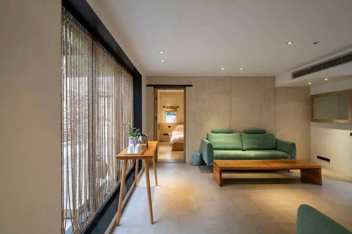 A modern living room with a green sofa, a wooden coffee table, and a small side table with decorative items.
