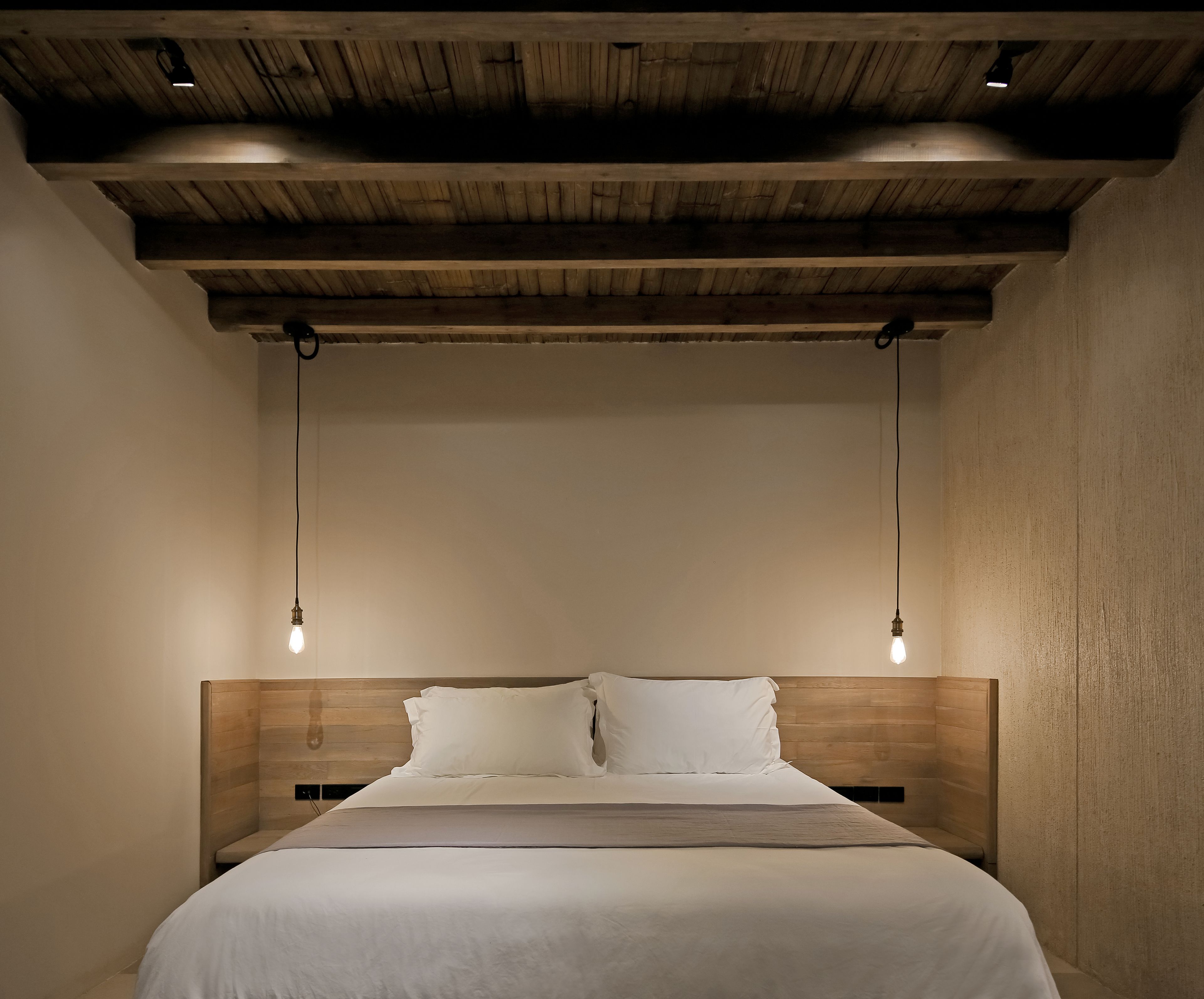 A bedroom with a wooden headboard, two bedside lamps, and a bed with white bedding.