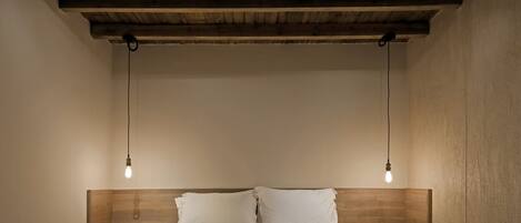 A bedroom with a wooden headboard, two bedside lamps, and a bed with white bedding.