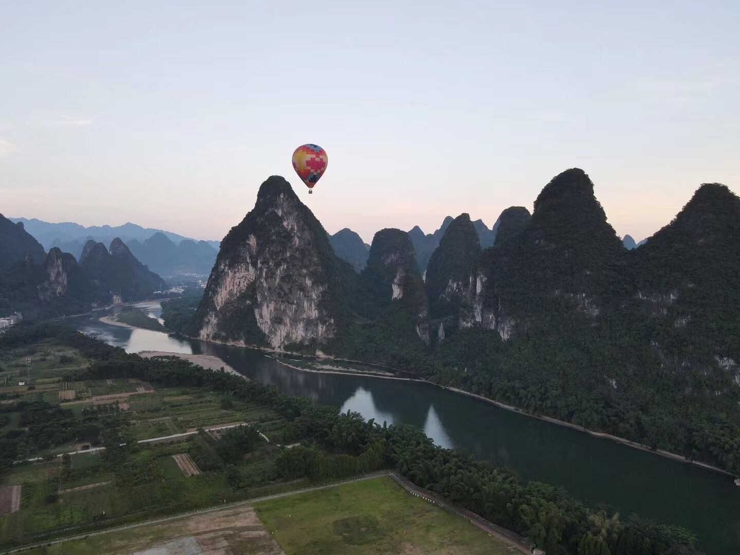 A hot air balloon over a mountainous landscape with a river.