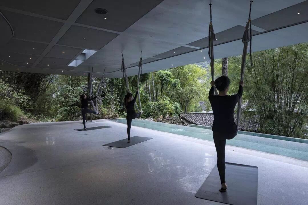 An indoor space with a modern ceiling design, large windows, and a view of a natural landscape.