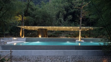 Una piscina al aire libre, una piscina infinita, sombrillas