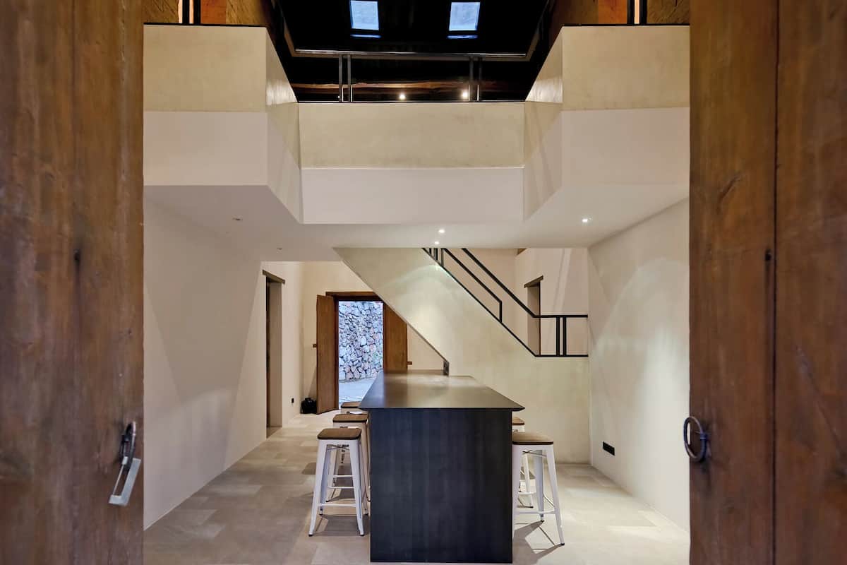 A modern interior with a central bar area, a staircase, and wooden paneling.