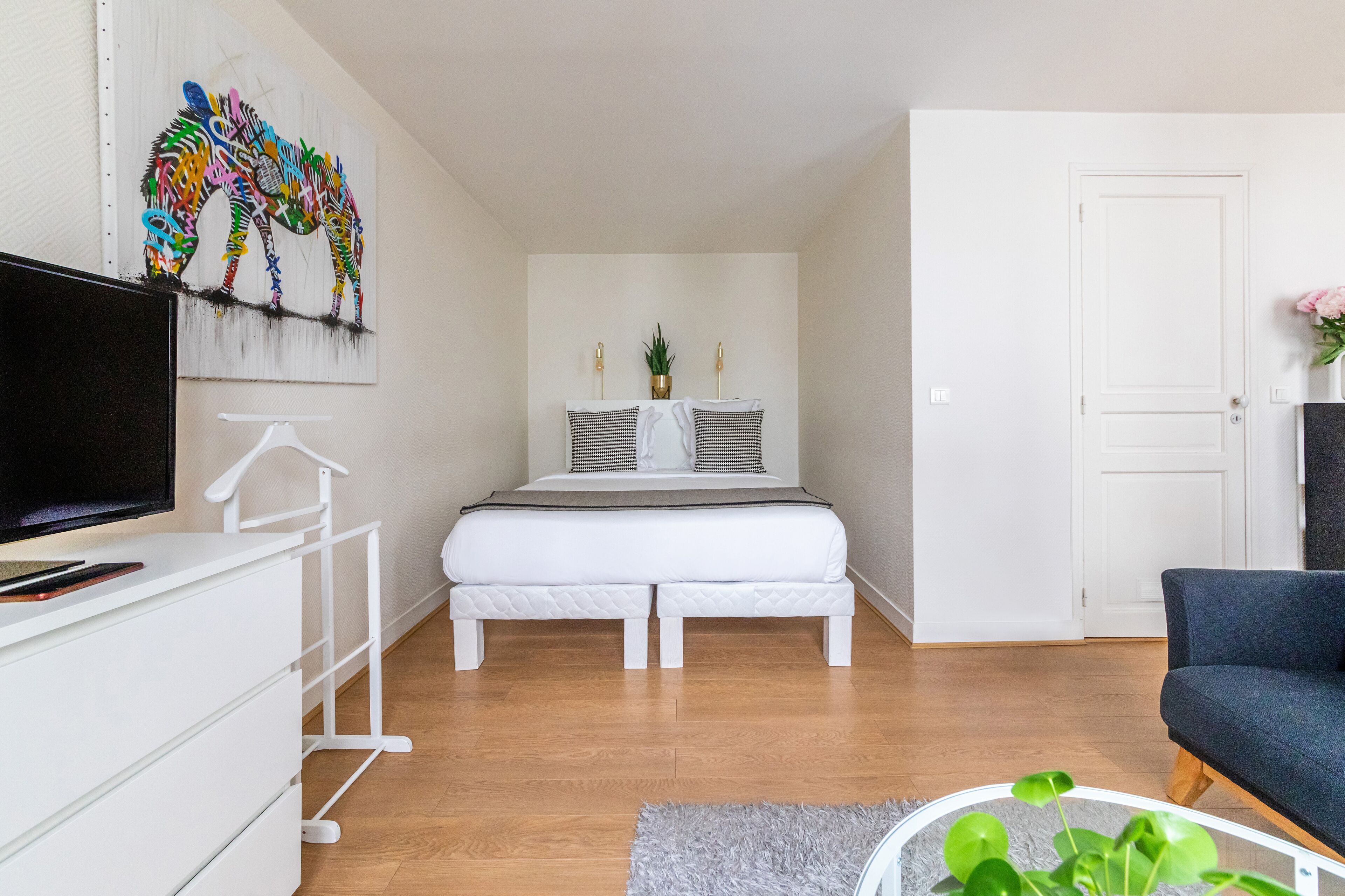 Ein modernes Schlafzimmer mit Bett, Fernseher, Schminktisch und einer Tür.