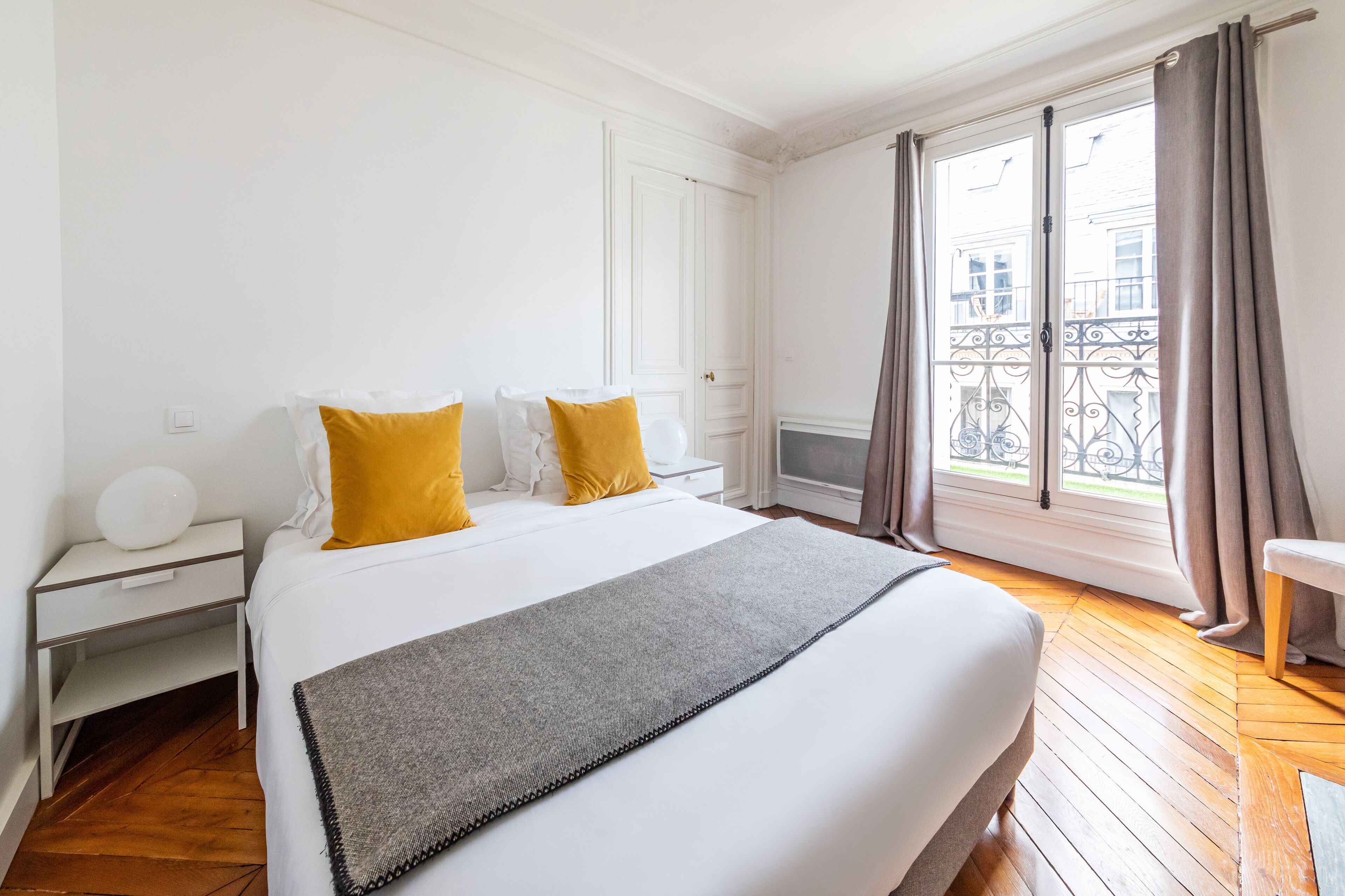 A hotel room with a bed, a nightstand, a chair, and a window with curtains.
