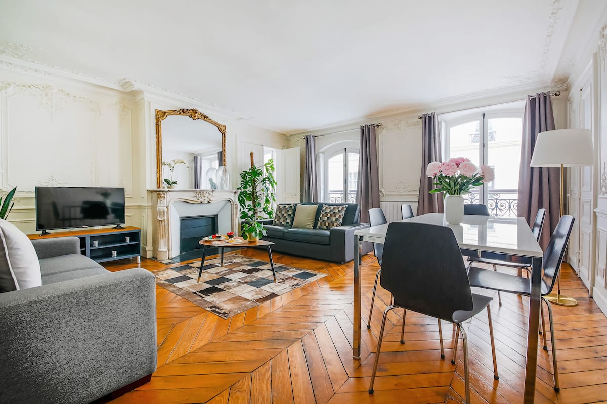 Un salon comprenant un canapé, un téléviseur, une table à manger, des chaises et une cheminée.