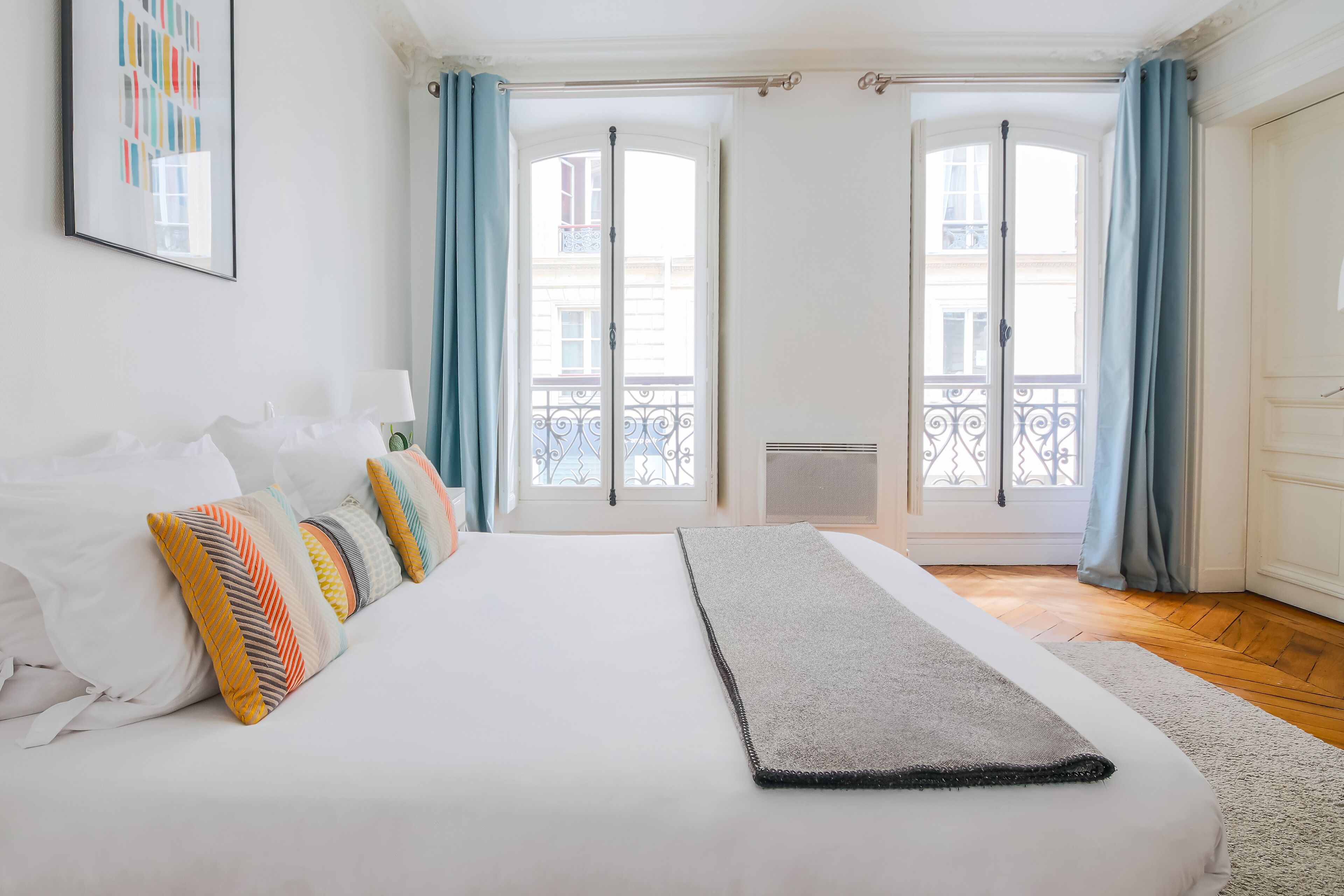 A bedroom with a large bed, a view of the outside balcony, and a door leading to the balcony.