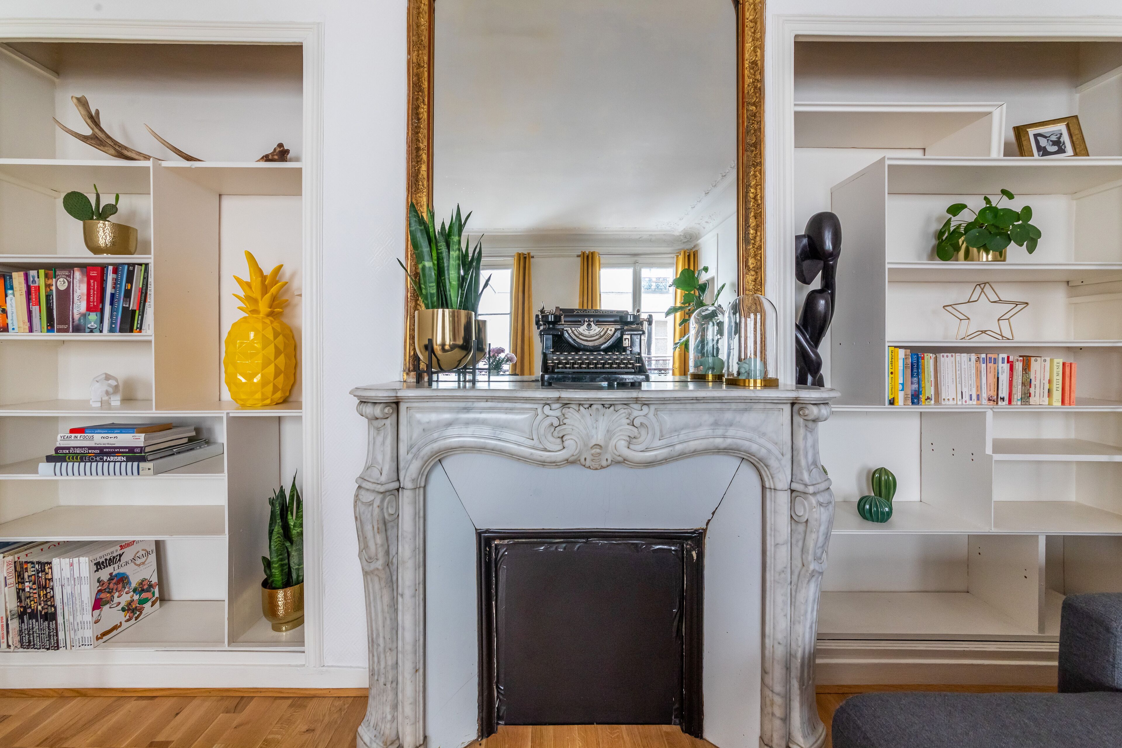 A living room with a fireplace, bookshelves, and decorative items.