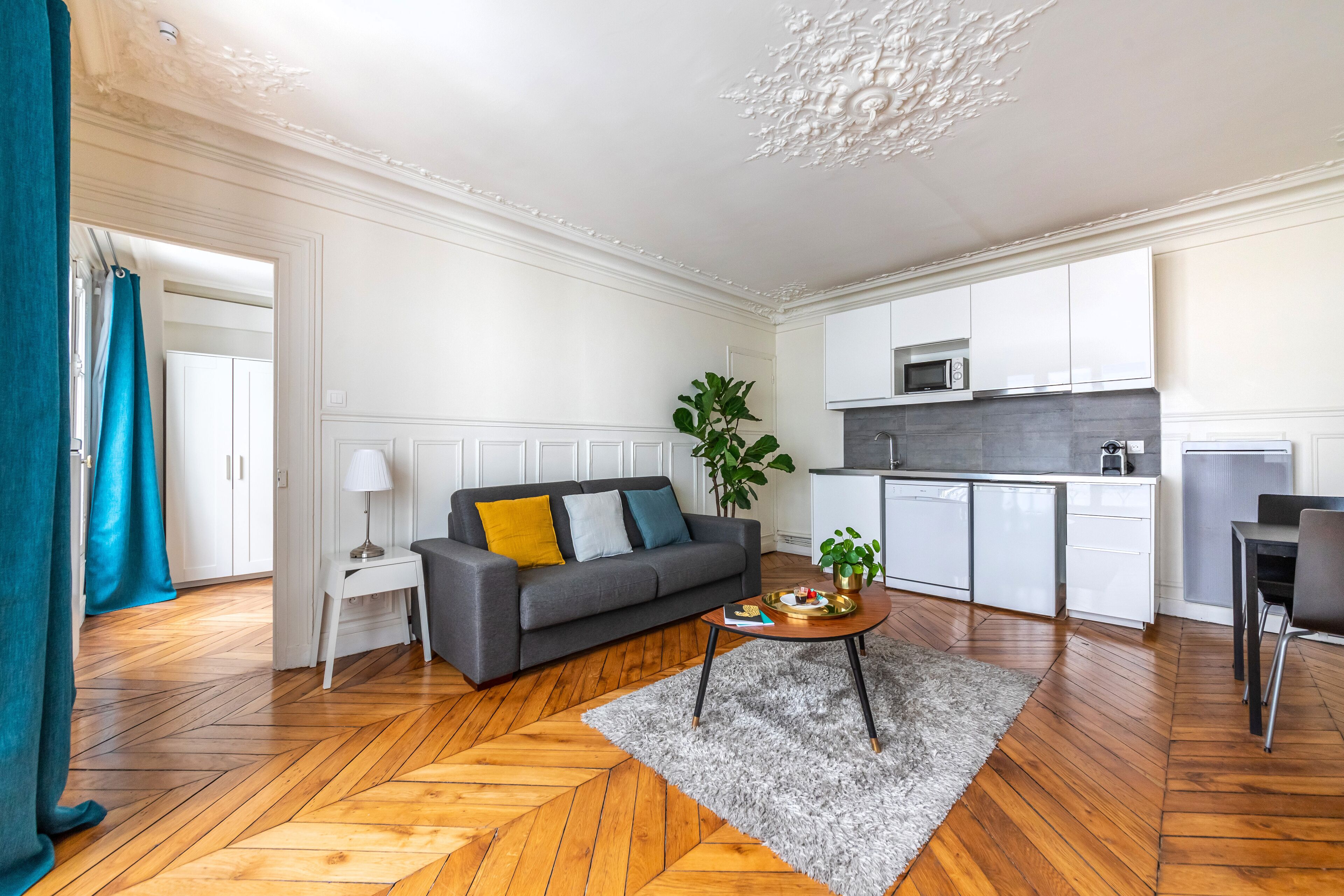 A modern living room with a sofa, a coffee table, and a kitchen area with cabinets and appliances.