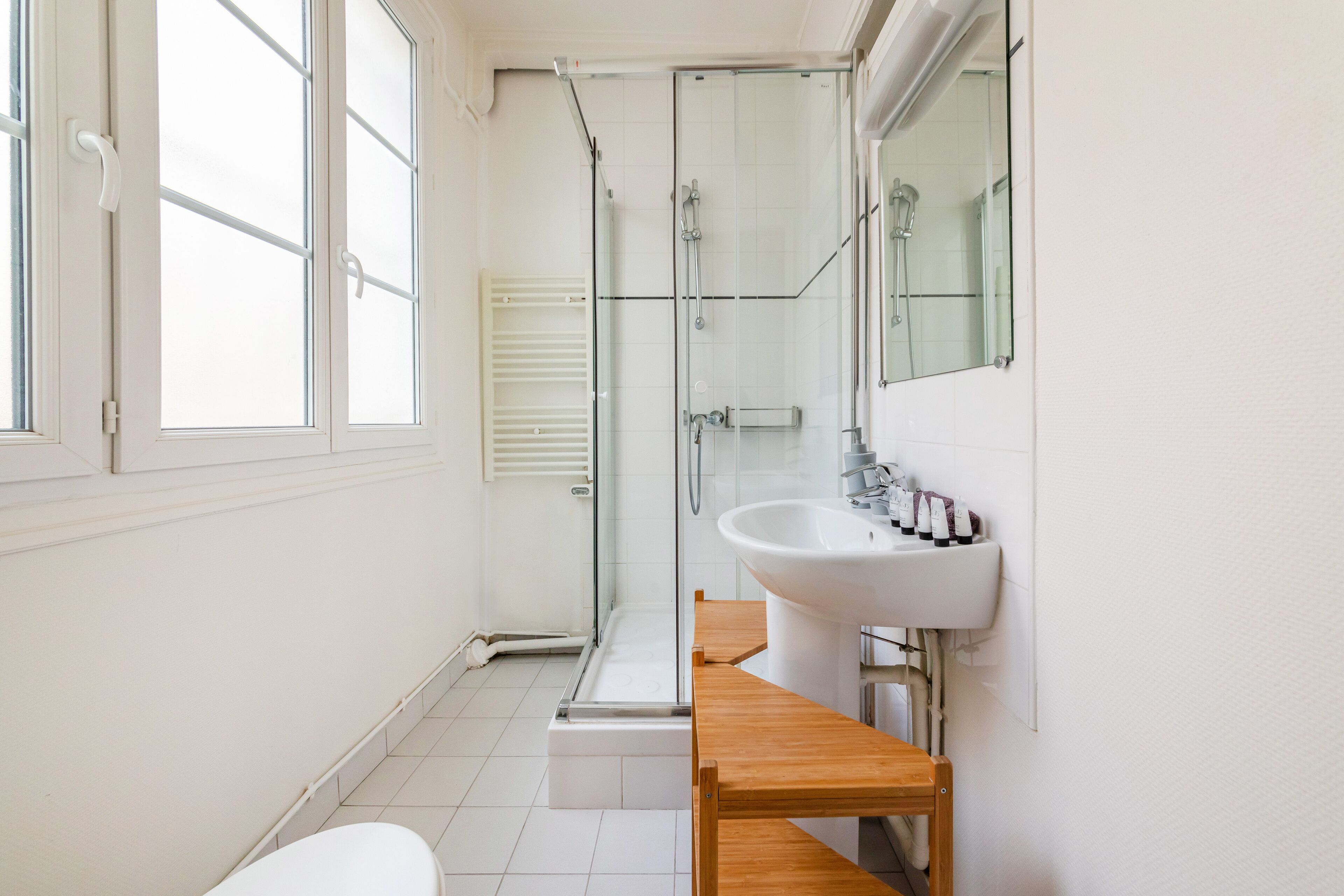 A modern bathroom with a glass shower enclosure, a white sink, and a wooden vanity.