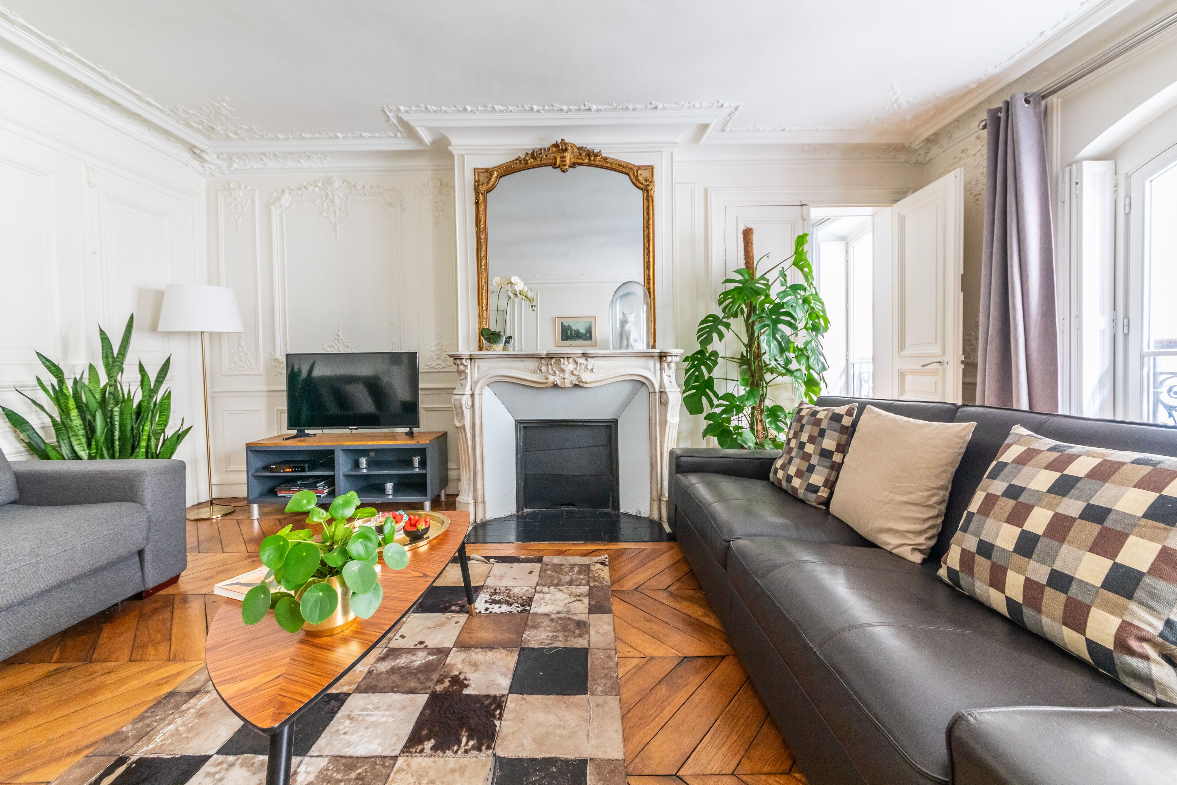 Una sala de estar con chimenea, un sofá, un televisor y una mesa de centro con plantas.