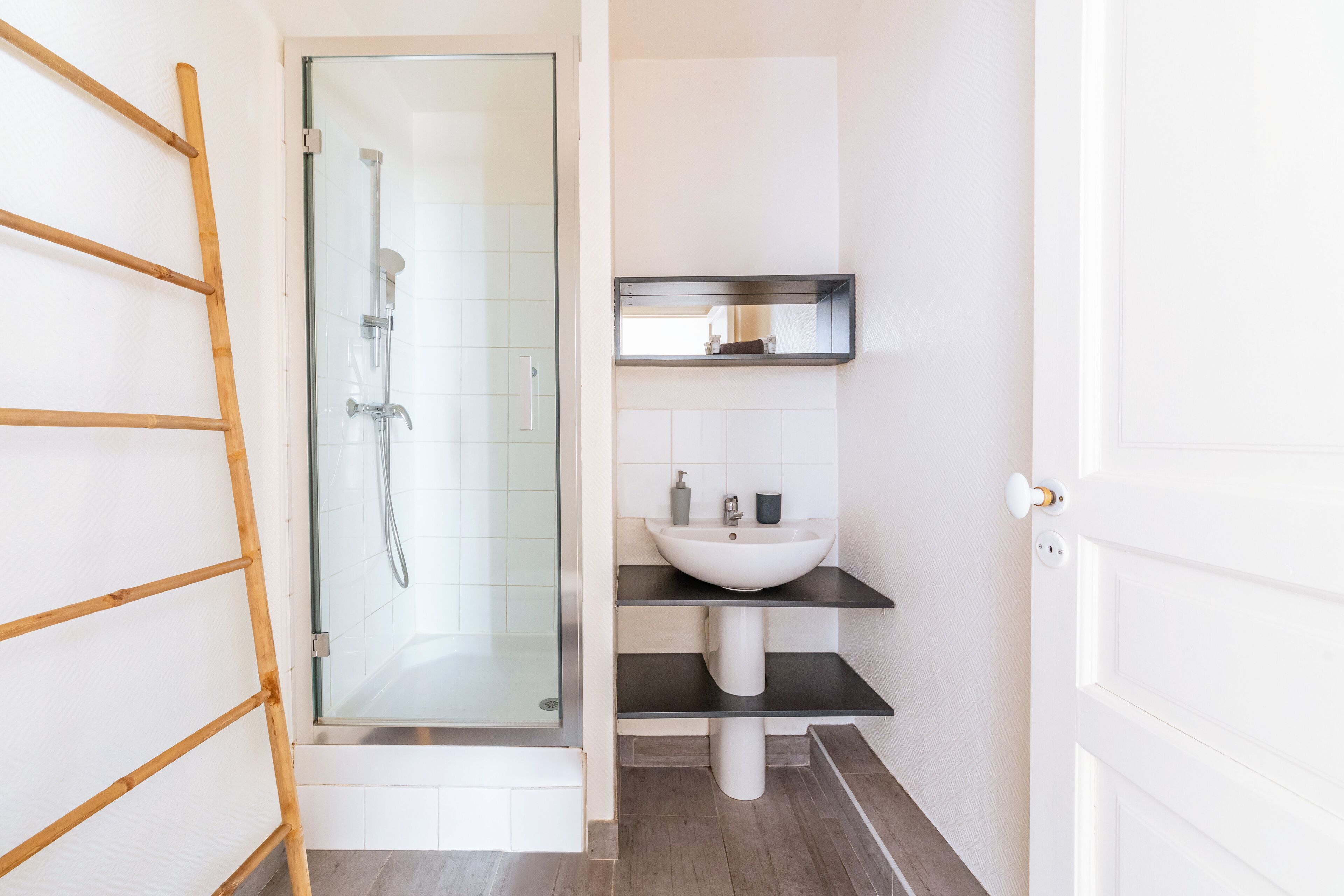 A bathroom with a glass-enclosed shower, a white sink, and a dark countertop.