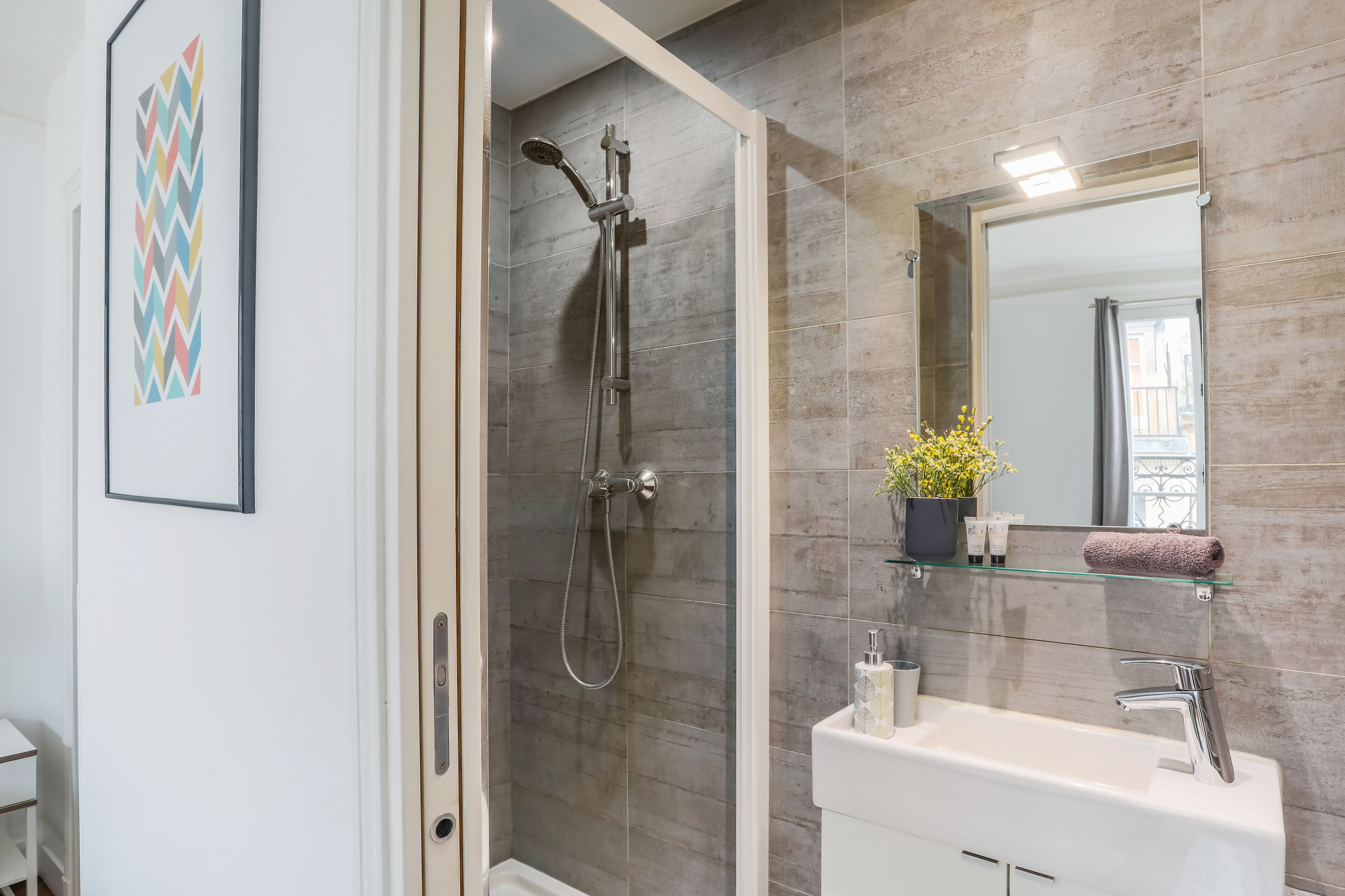Un baño moderno con ducha, lavamanos y espejo.