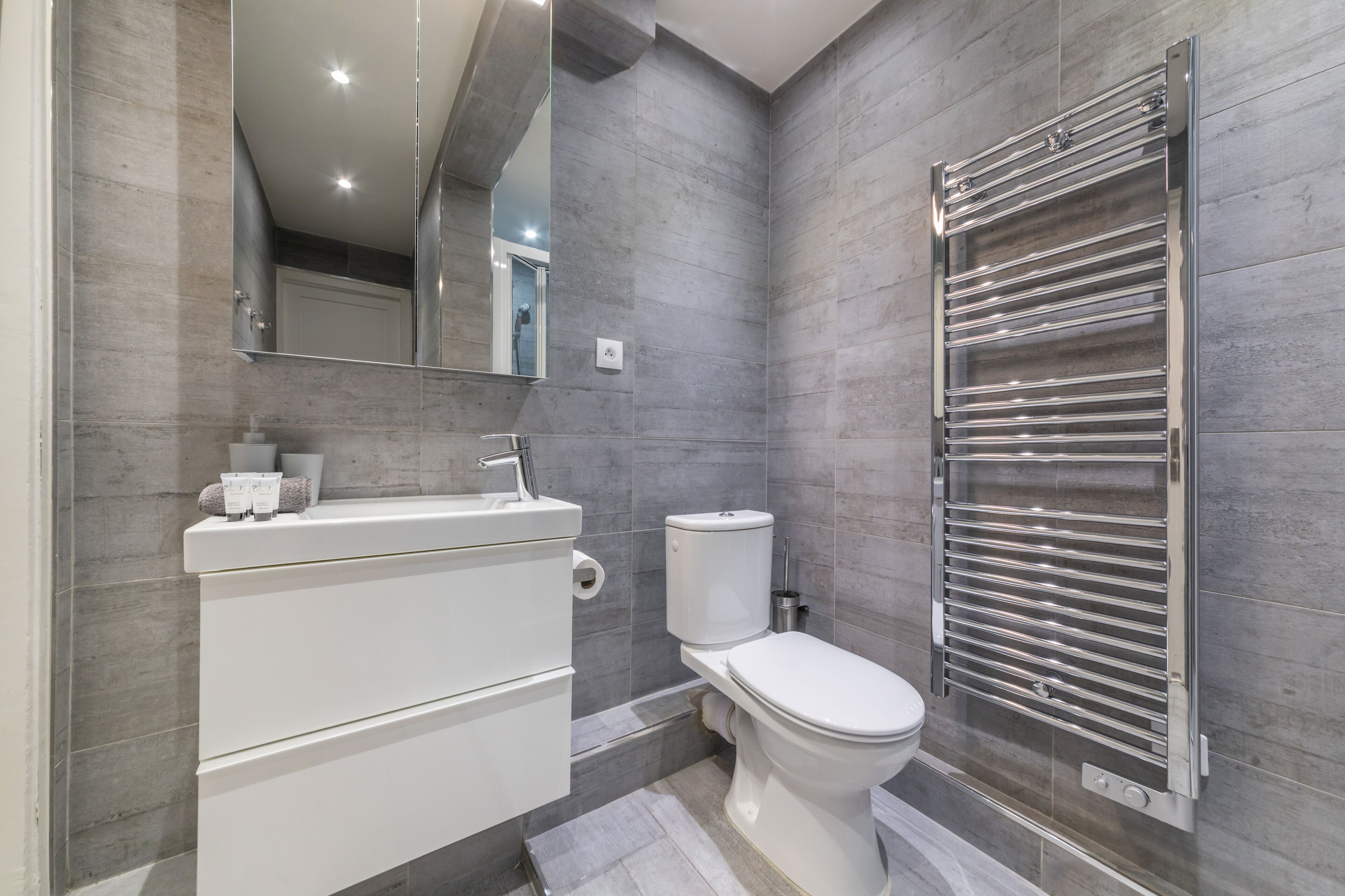 A modern bathroom with a white sink, toilet, and a towel rack.