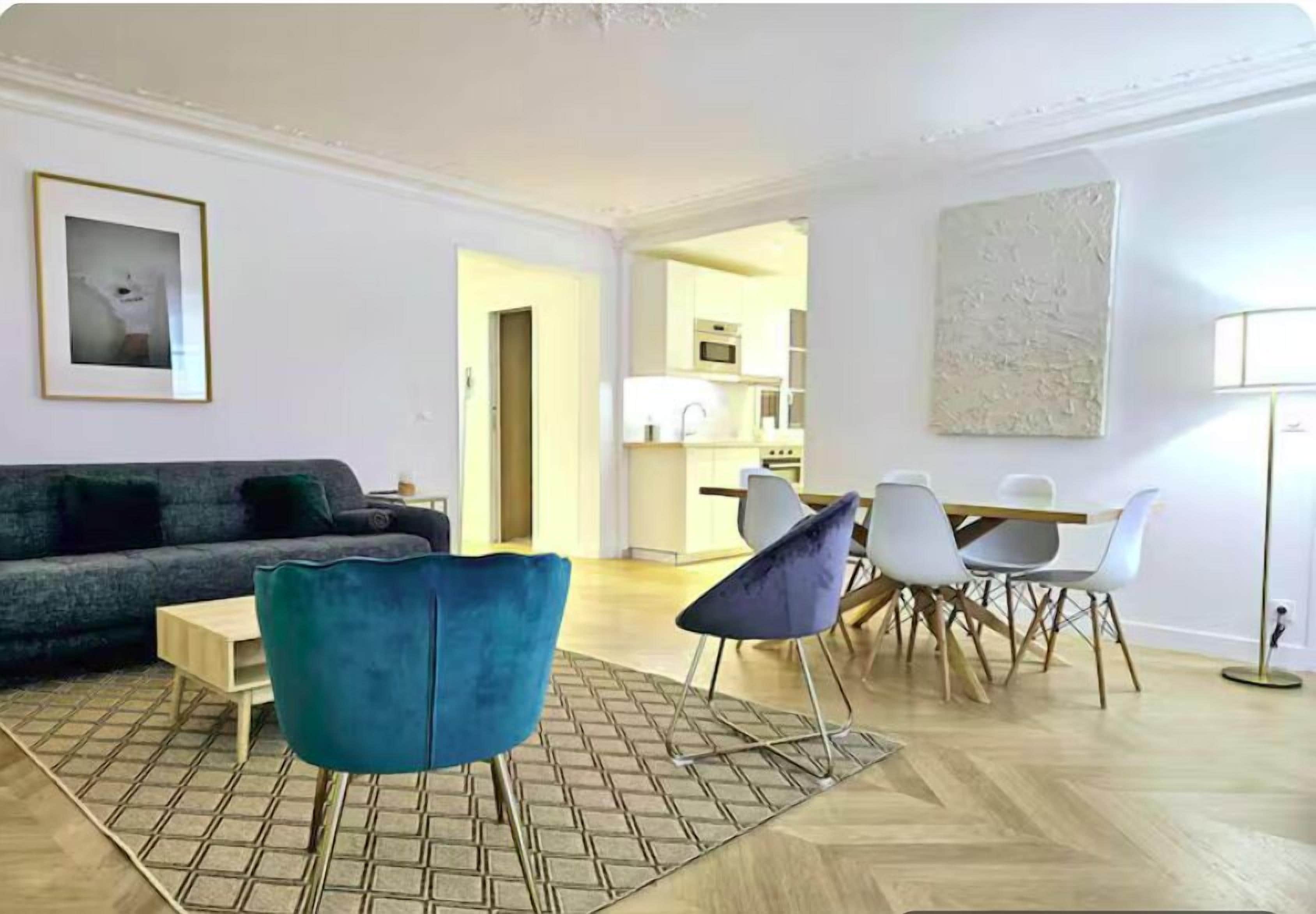 A modern living room with a sofa, a coffee table, and a dining area with chairs and a table.