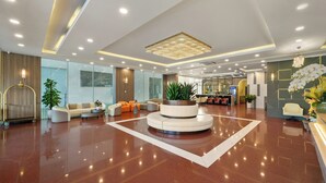 A spacious lobby with a central seating area, a reception desk, and a large chandelier. - Lunar Hotel Danang (Da Nang)
