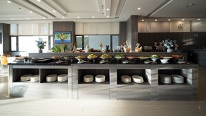 A modern kitchen with a central island, multiple dishware storage shelves, and a variety of food items displayed. - Lunar Hotel Danang (Da Nang)