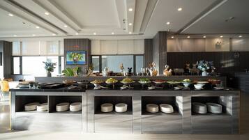 A modern kitchen with a central island, multiple dishware storage shelves, and a variety of food items displayed.