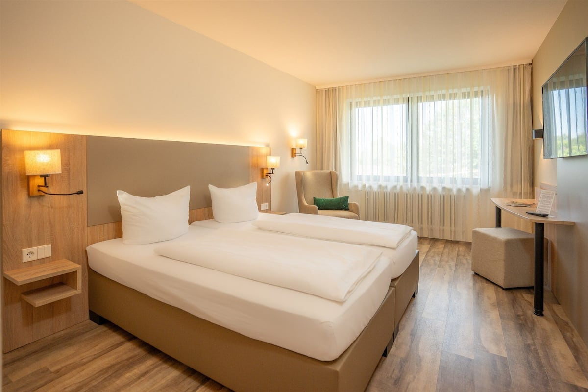 Une chambre d’hôtel avec un grand lit, des lampes de chevet, un bureau et une chaise.